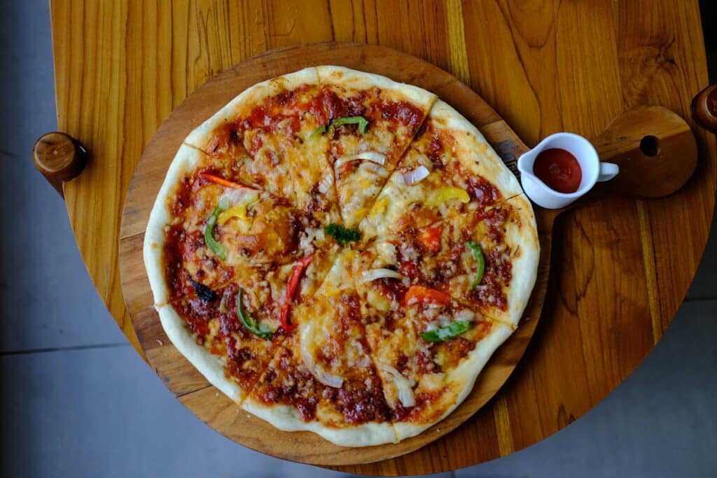a pizza sitting on top of a wooden table a pizza sitting on top of a wooden table